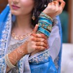 A bride showcases intricate henna designs and vibrant jewelry in traditional attire.